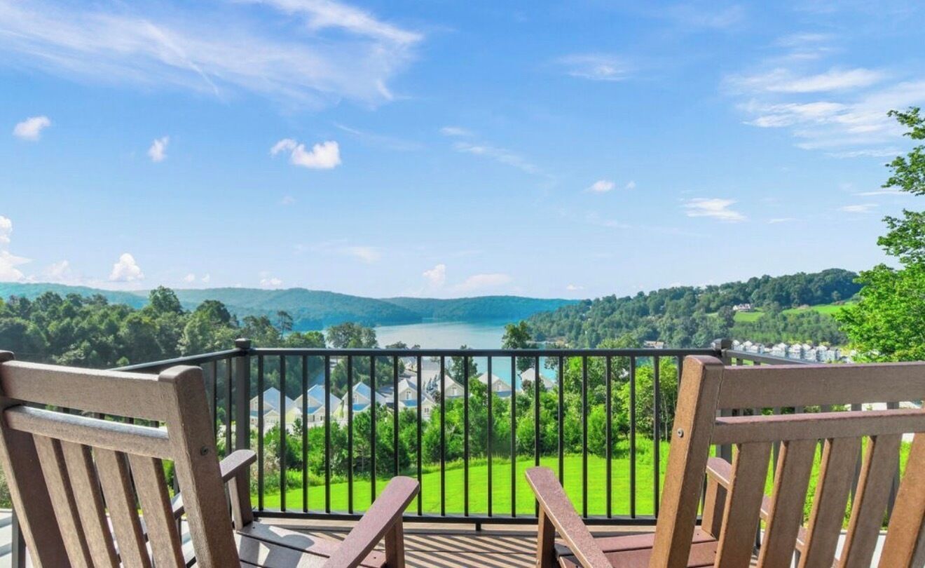 En balkon med to træstole, der vender ud mod et smukt udsigtspunkt over en sø og bjerge.