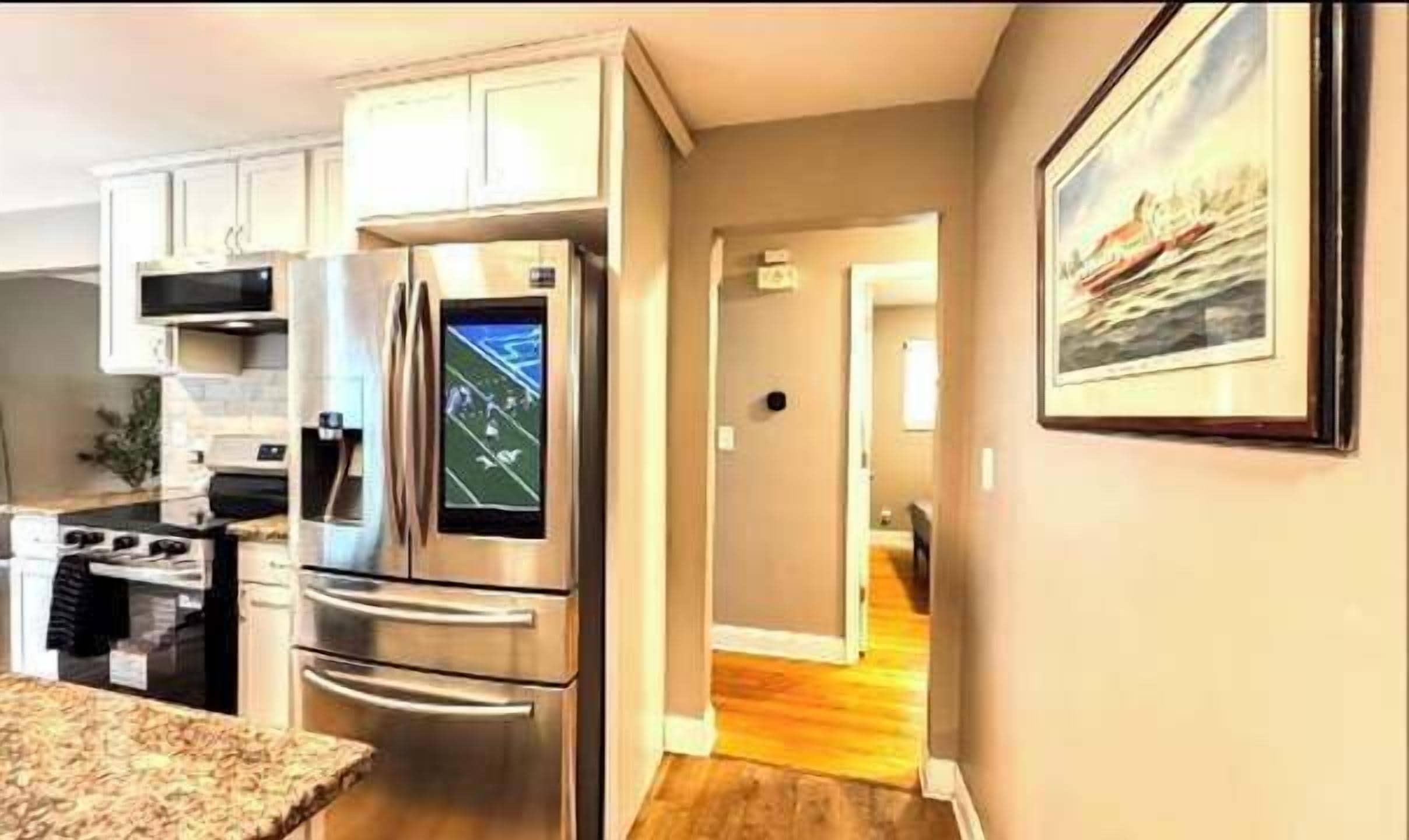 Una cucina moderna con elettrodomestici in acciaio inossidabile, un piano di lavoro in granito e un corridoio che porta a un'altra stanza.