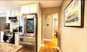 Una cocina moderna con electrodomésticos de acero inoxidable, encimera de granito y un pasillo que conduce a otra habitación.