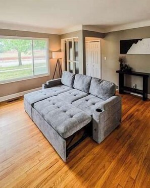 Ein modulares Sofa in einem Raum mit Holzdielen, einer Tür und einem Fenster.