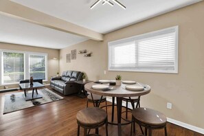 A dining area with a round table, four stools, and a sofa in the background. - Chic 2BR Oasis - Downtown Birmingham (Birmingham)