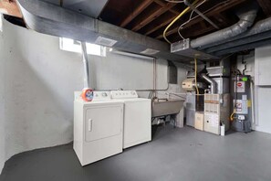 A laundry room with a washing machine, dryer, and stacked laundry baskets. - Chic 2BR Oasis - Downtown Birmingham (Birmingham)