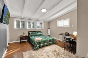 A bedroom with a bed, a desk, a chair, a TV, and a window. - Chic 2BR Oasis - Downtown Birmingham (Birmingham)