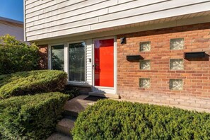 A modern building with a red door, brick facade, and a small front porch. - Chic 2BR Oasis - Downtown Birmingham (Birmingham)