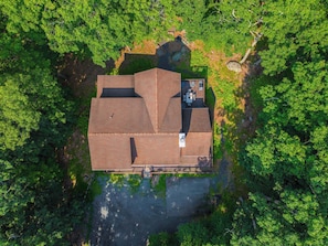 Luchtbeeld van een huis met een centrale binnenplaats, omgeven door weelderige begroeiing.