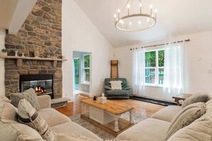 A cozy living room with a stone fireplace, a green armchair, and a wooden coffee table.