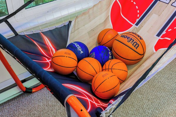 A basket filled with basketballs and a basketball hoop.
