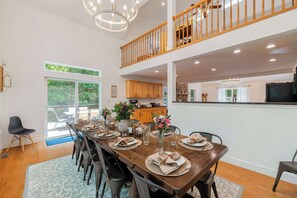 A dining area with a long wooden table set for four, surrounded by chairs.