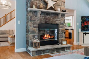 A stone fireplace with a star decoration, a framed picture, and a lantern on the mantel.