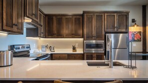 A modern kitchen with wooden cabinets, stainless steel appliances, and a marble countertop. - Paso Park Suites by Avantstay On the Park + Walk to Downtown Dining Downtown Paso Robles (Paso Robles)