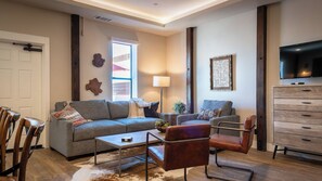 A modern living room with a sofa, armchair, coffee table, and a TV. - Paso Park Suites by Avantstay On the Park + Walk to Downtown Dining Downtown Paso Robles (Paso Robles)