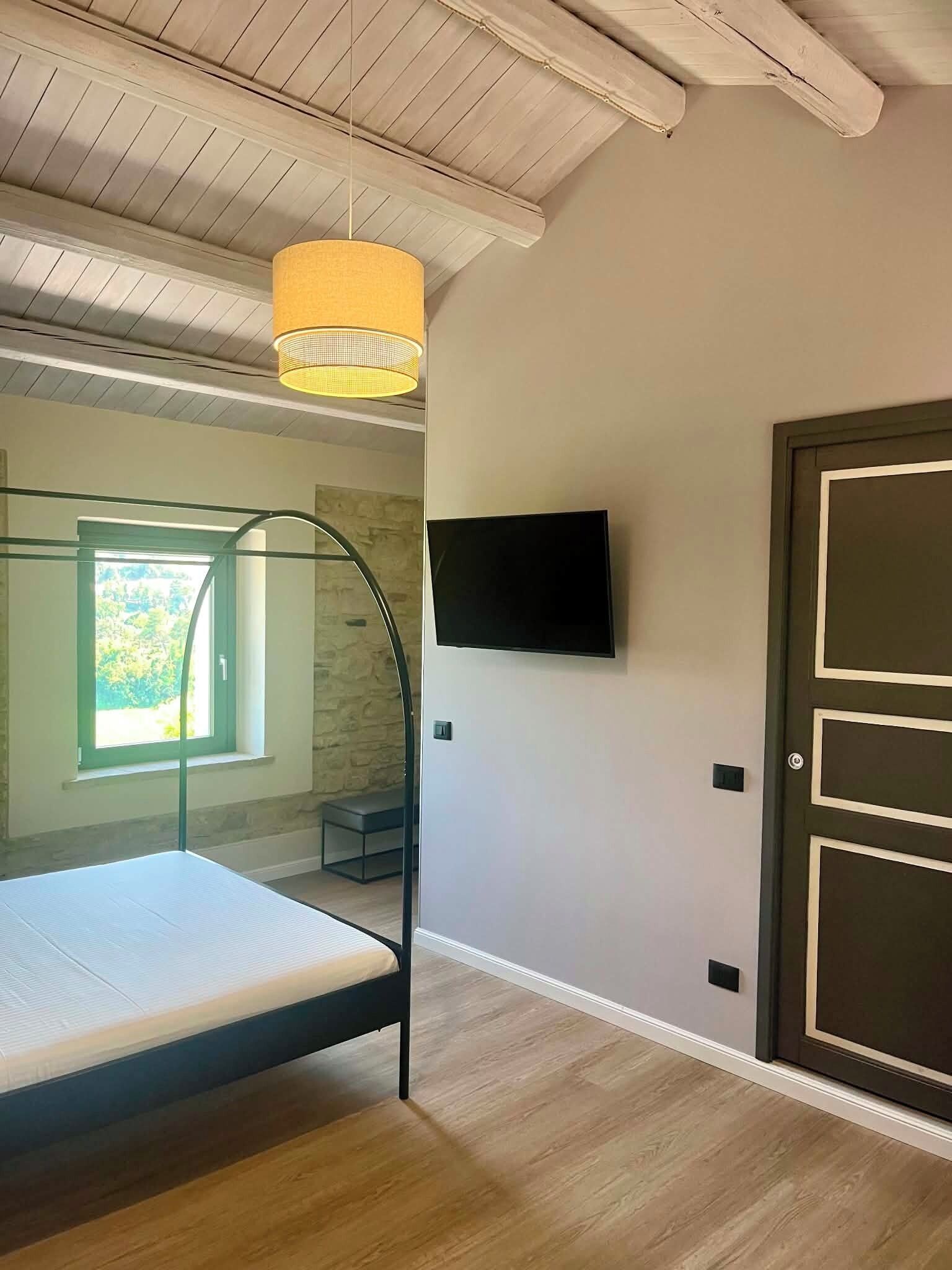 Een slaapkamer met een stapelbed, een aan de muur bevestigde televisie en een deur met een hendel.