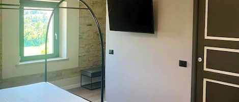 Quarto com uma cama beliche, televisão na parede e porta com puxador.