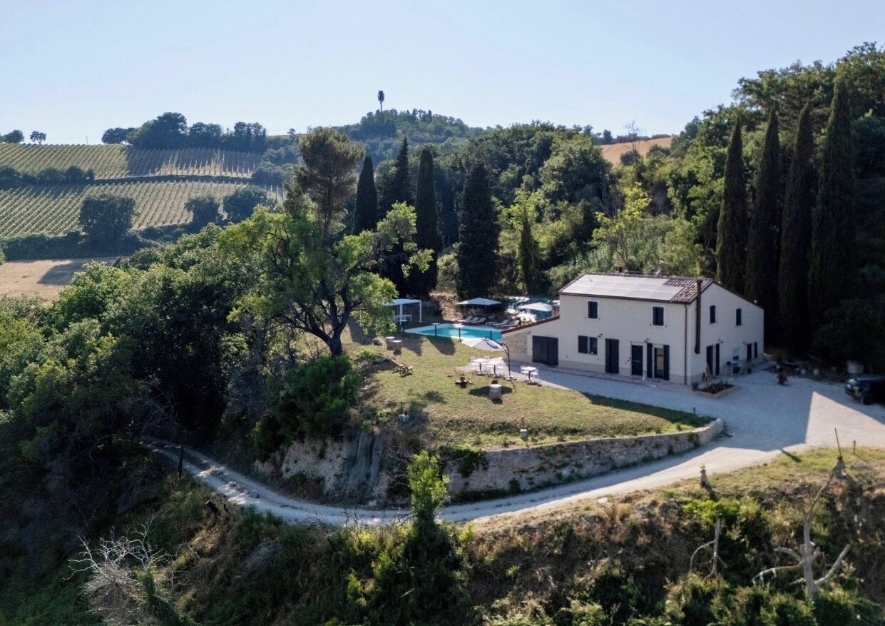 Eine Villa mit Swimmingpool, umgeben von üppiger Vegetation und einer hügeligen Landschaft.