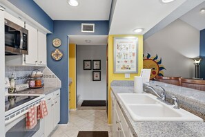 A kitchen with a microwave, oven, and sink. There is a framed menu on the wall and a door leading to another room. - Stunning Lake Conroe 3BR Escape w/ Pool Access (Montgomery)