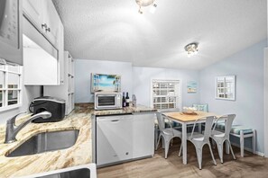 Eine moderne Küche mit Spüle, Mikrowelle, Geschirrspüler und einem Essbereich mit Tisch und Stühlen.