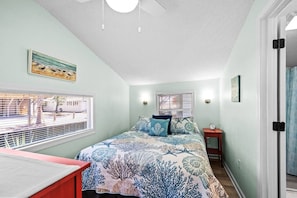 A bedroom with a bed, a window, a bedside table, and a door. - 1002 Seaside Cottage (Myrtle Beach)