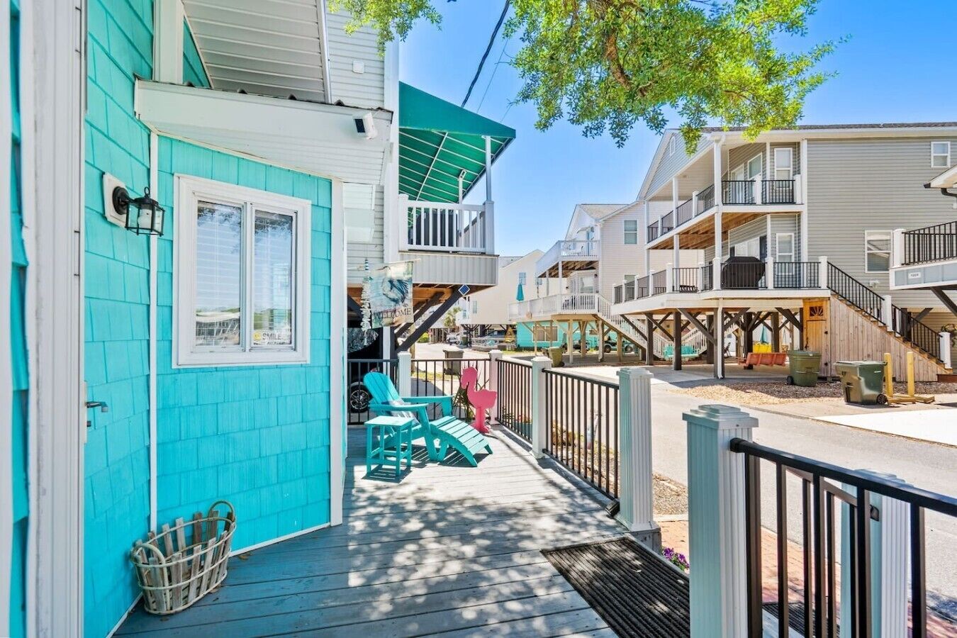 A turquoise building with a porch, a welcome sign, and a staircase leading to an upper level.