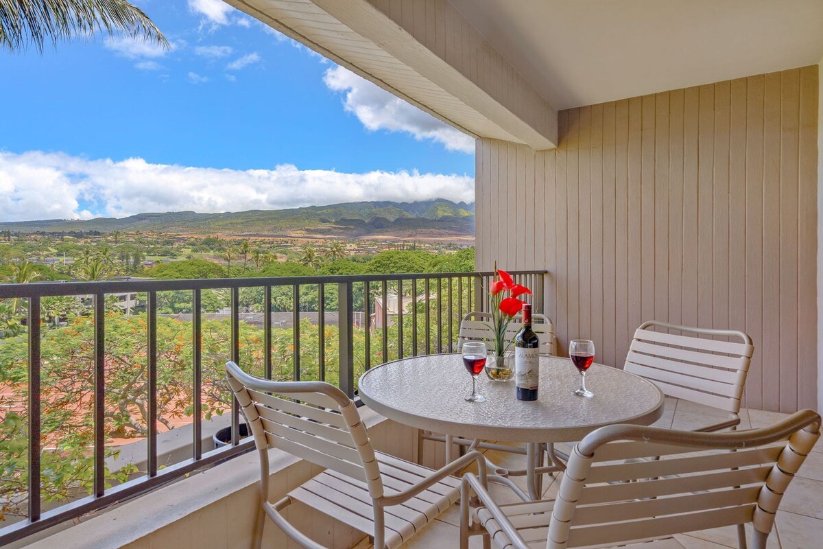 A balcony with a round table and chairs, a bottle of wine, and a glass of red wine.