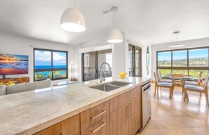 Una cocina moderna con una isla grande, armarios de madera y vistas al océano.