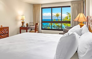 A hotel room with a large bed, a desk with a lamp, and a window with a view of the ocean. - The Kaanapali Alii by Maui Resort Rentals (Kaanapali)