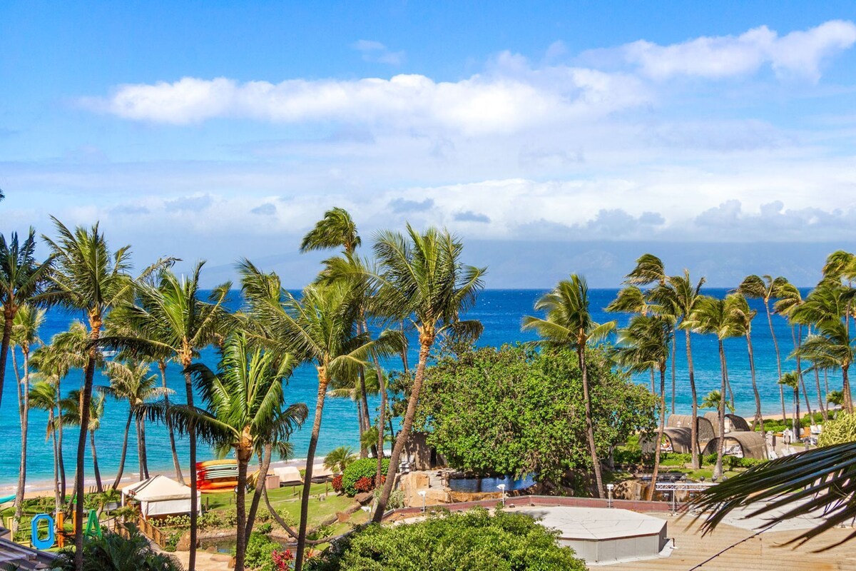A tropical beach with palm trees, a clear blue sky, and a view of the ocean.