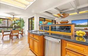 A modern kitchen with wooden cabinets, a built-in dishwasher, and a large island with a sink. - The Kaanapali Alii by Maui Resort Rentals (Kaanapali)