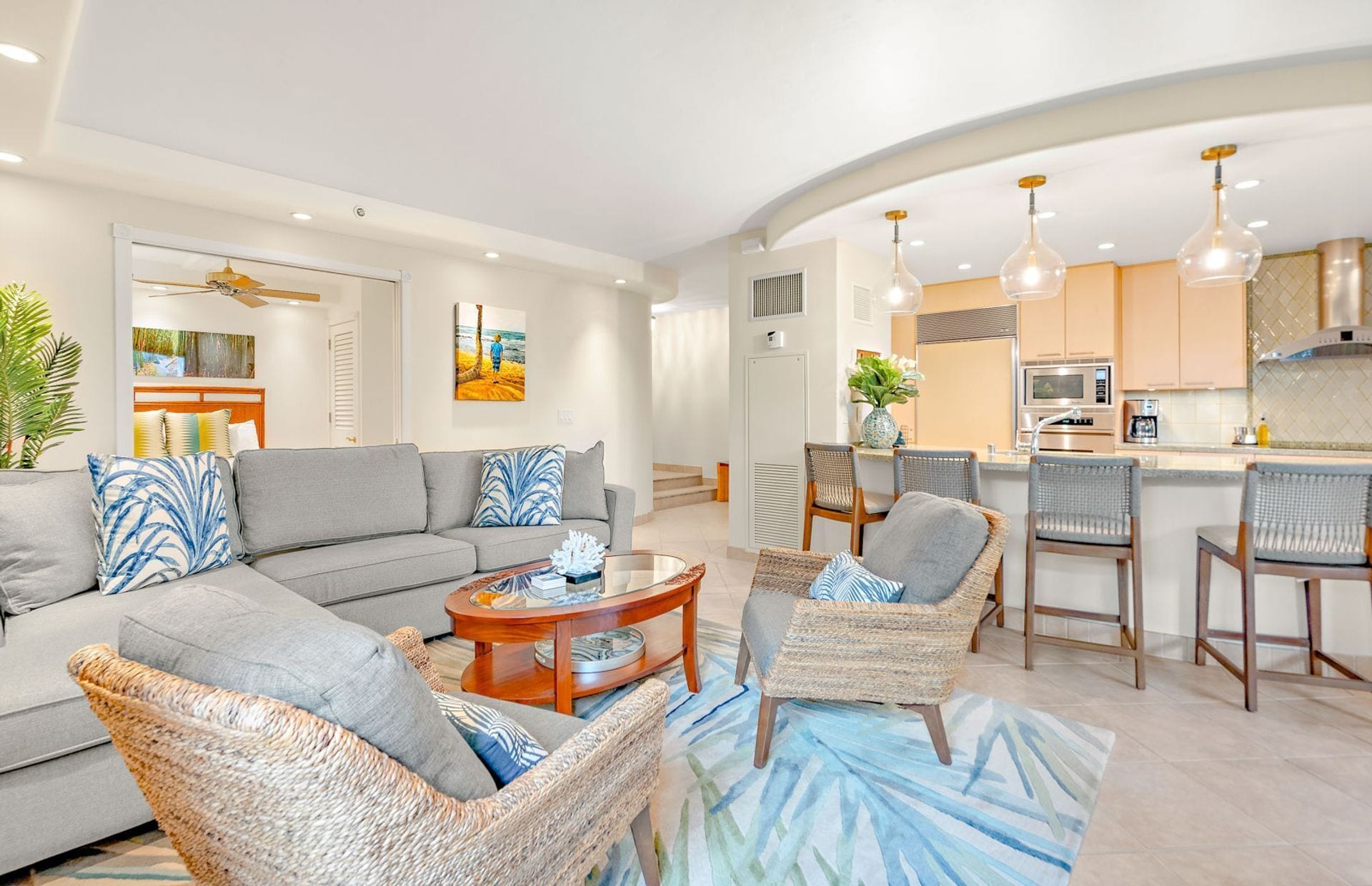 A modern living room with a sofa, chairs, a coffee table, and a kitchen area with bar stools.