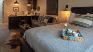 Ein gemütliches Schlafzimmer mit einem großen Bett, einem Schreibtisch und einem Stuhl. Auf dem Bett steht ein Tablett mit einer Rose und einer Tasse.