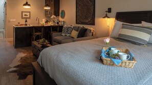 A cozy bedroom with a large bed, a desk, and a chair. There is a tray with a rose and a cup on the bed. - Paso Park Suites by Avantstay Park-view Balcony Downtown Paso Robles (Paso Robles)