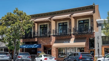 Un edificio de varios pisos con fachada de ladrillo, locales comerciales y balcones.