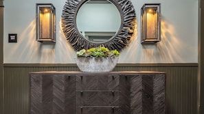 A bathroom vanity with a mirror, two wall-mounted lights, and a plant in a stone bowl. - Paso Park Suites by Avantstay Park-view Balcony Downtown Paso Robles (Paso Robles)