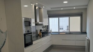 Eine moderne Küche mit Edelstahlgeräten, weißen Schränken und einem großen Fenster, das für natürliches Licht sorgt.