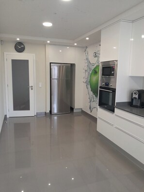 A modern kitchen with a stainless steel refrigerator, a microwave, and a coffee machine. - Beautiful Atlantic Days (Moledo)
