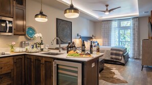 A modern kitchen with a central island, a dining area with a bed, and a ceiling fan. - Paso Park Suites by Avantstay Balcony Over the Square + Walkable Paso Robles (Paso Robles)