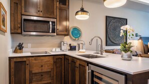 Una cucina moderna con mobili in legno, un forno a microonde in acciaio inossidabile, una macchina da caffè e un lavello.