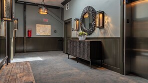 A hallway with a wooden bench, a map on the wall, and an elevator. - Paso Park Suites by Avantstay Balcony Over the Square + Walkable Paso Robles (Paso Robles)