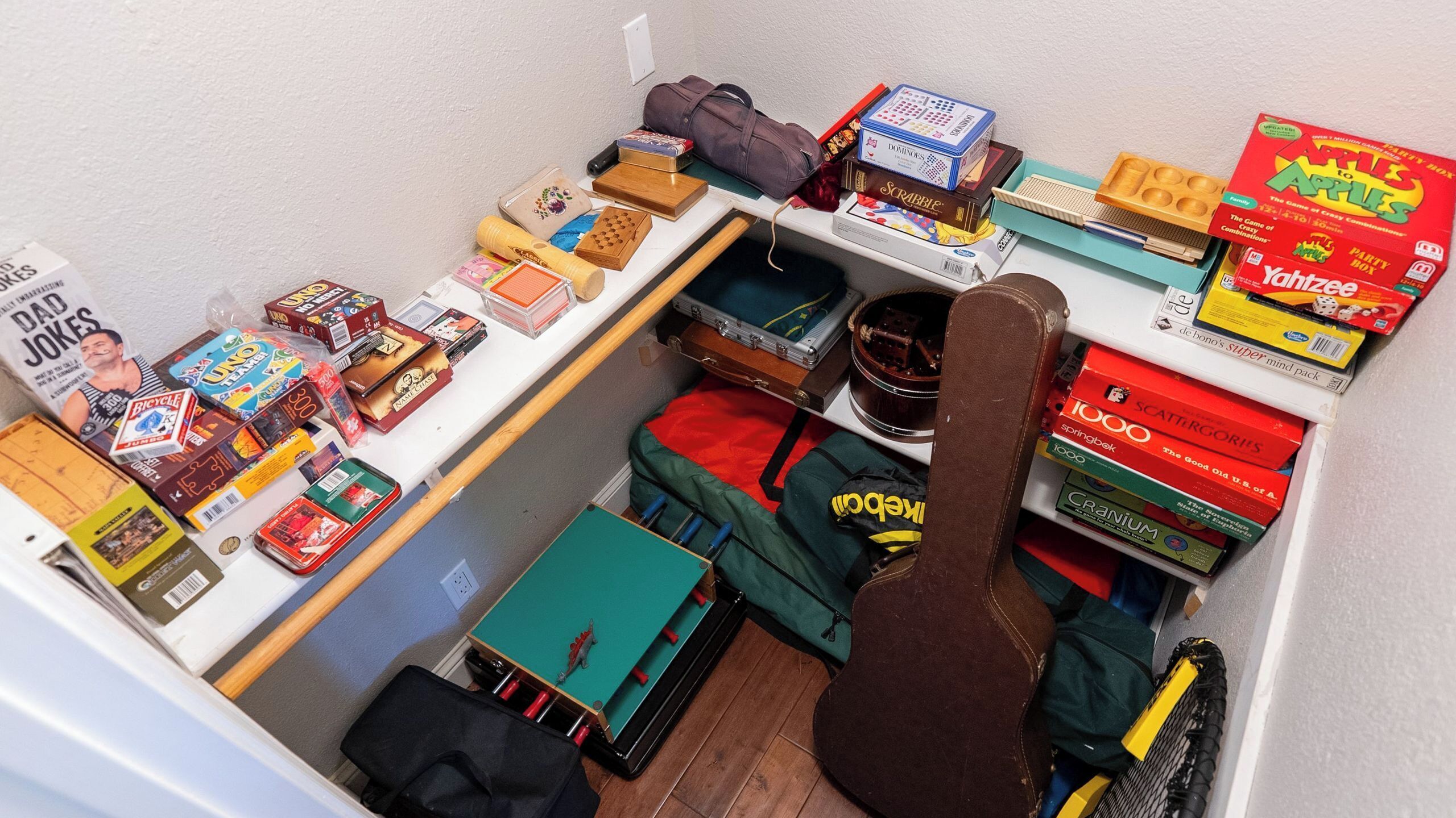 A small room with a variety of board games, a guitar, and a suitcase.