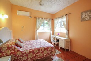 A bedroom with a bed, a desk, and a window with curtains.