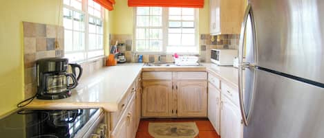 Una cocina equipada con estufa, horno, refrigerador y cafetera.