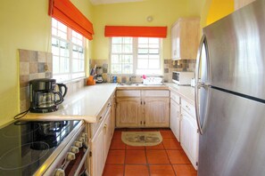 A kitchen with a stove, oven, refrigerator, and a coffee maker.