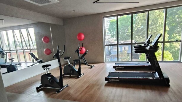 Un gimnasio con cintas de correr, bicicletas estáticas y pelotas de ejercicios.