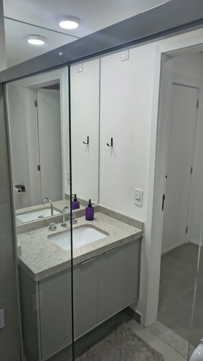 Une salle de bain avec un grand miroir, un lavabo et une douche.