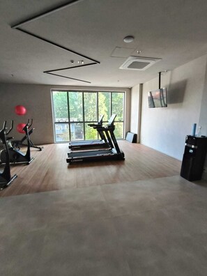 Une salle de sport équipée de tapis de course, de vélos d’appartement et de ballons d’exercice.