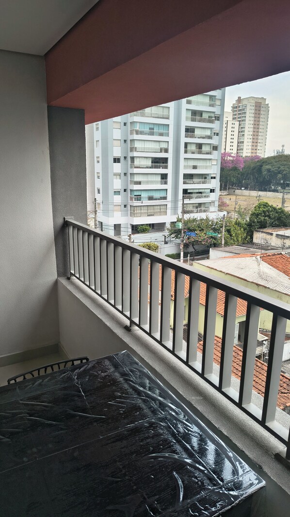 A balcony with a view of a multi-story building and a street below.