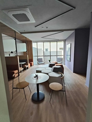 A modern interior with a round table, multiple chairs, and a large window providing natural light.