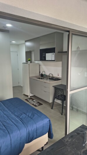A compact room with a bed, kitchenette, and a small dining area.