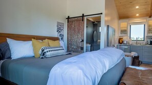 A bedroom with a large bed, a wooden headboard, and a sliding door leading to a bathroom. - Cocavin Carriage House by Avantstay Gated Vineyard Ranch + Fire Pit + BBQ Paso Robles (Paso Robles)