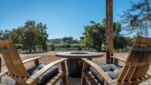 A circular outdoor seating area with a fire pit, surrounded by wooden chairs with cushioned seats. - Cocavin Carriage House by Avantstay Gated Vineyard Ranch + Fire Pit + BBQ Paso Robles (Paso Robles)