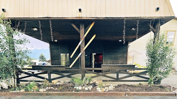 A rustic wooden building with a covered porch, a wooden fence, and a small garden area. - Eagle Nest Inn & Apartments (Eagle Nest)